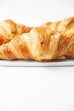 Close up of croissants on plate on table and white background, vertical, with copy space