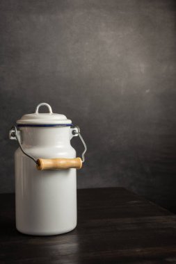 Koyu ahşap masadaki antika beyaz süt sürahisini kapat. Gri arka plan, kopya alanı ile dikey.
