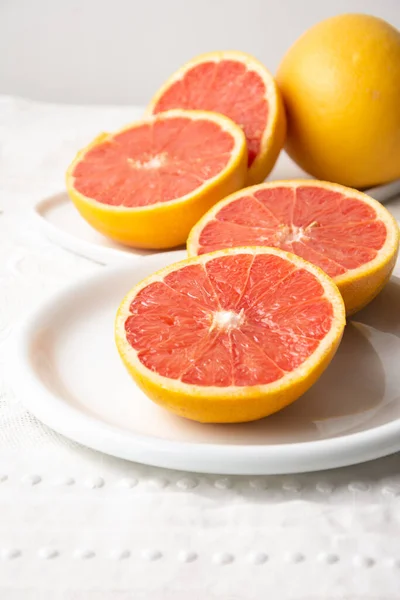 Draufsicht Auf Gespaltene Rote Grapefruits Auf Teller Und Weißer Tischdecke — Stockfoto
