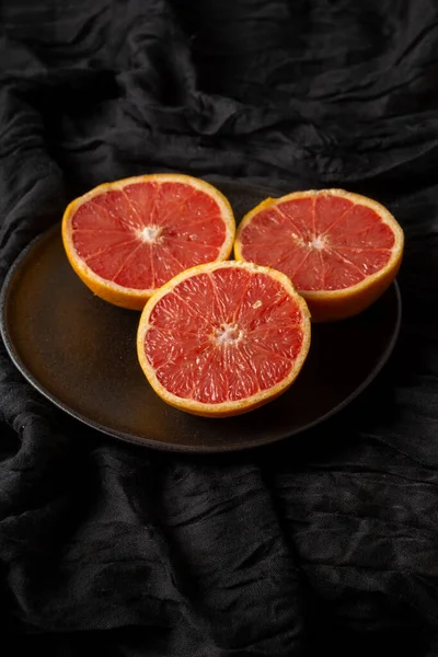 Ansicht Von Gespaltenen Grapefruits Auf Teller Und Schwarzem Tuch Vertikal — Stockfoto