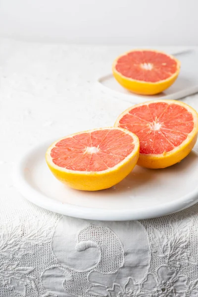 Draufsicht Auf Geschnittene Rote Grapefruits Auf Teller Und Weißer Tischdecke — Stockfoto