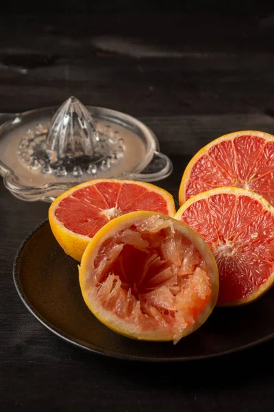 Nahaufnahme Geschnittener Grapefruits Auf Schwarzem Teller Mit Glasentsafter Auf Dunklem — Stockfoto