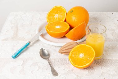 Dilimlenmiş portakallı tabağın üst görüntüsü ve portakal suyu, meyve suyu, kaşık ve bıçak ile beyaz masa örtüsü, yatay ve fotokopi alanı olan cam.