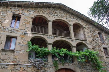 Balkonunda yeşil bitkiler olan geleneksel bir Katalan çiftlik evinin ön yüzü, yatay.