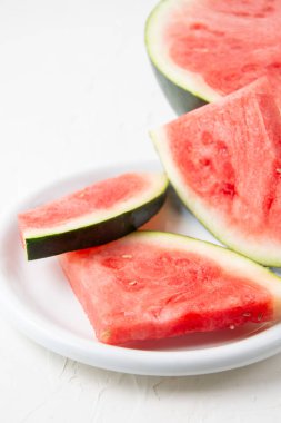Tabakta kırmızı karpuz dilimleri ve beyaz arka plan, dikey, kopyalama alanı ile yakın plan