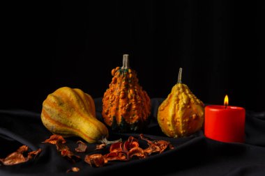 Masa örtüsü üzerinde turuncu mum bulunan üç balkabağı görüntüsü ve siyah arkaplan, yatay, kopyalama alanı ile