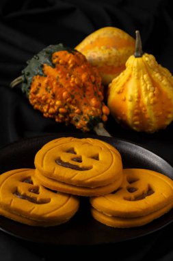 Balkabağı kurabiyelerinin üst görüntüsü ve siyah masa örtüsü üzerinde çikolata, üç balkabağı, dikey, kopyalama alanı ile