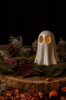 Güz yapraklı, siyah arka planlı, dikey, masasında ışık olan bir hayaletin üst görüntüsü.
