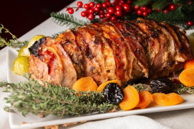 Close-up of turkey stuffed with dried apricots, sauce, potatoes, thyme and pomegranate seeds, with Christmas decoration on white tablecloth, horizontal clipart