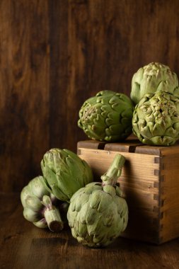 Masada enginar ve tahta arkaplan olan tahta kutu görüntüsü, dikey, kopyalama alanı ile