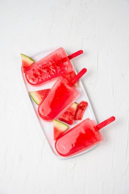 Beyaz tabakta üç karpuz lolipopunun havadan görünüşü, beyaz arkaplan, dikey, kopyalama alanı ile birlikte.