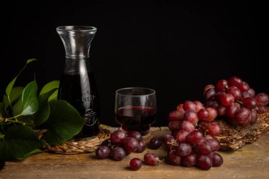 Kırsal şişenin üst görüntüsü, kırmızı şarap ve üzümlü ahşap masa, siyah arkaplan, yatay, fotokopi alanı olan