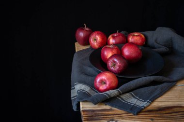 Üzerinde kırmızı elmalar olan kırsal tablonun üst görünümü, siyah arkaplan, yatay, kopyalama alanı olan