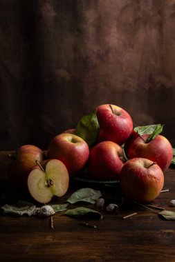 Masadaki kırmızı elma ve kuru yaprakların üst görünümü, koyu arkaplan, dikey, kopyalama alanı ile