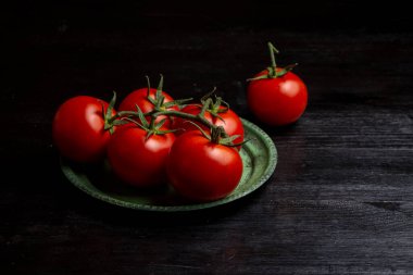 Yeşil tabakta domateslerin üst görüntüsü karanlık masa üzerinde, yatay kopya alanı ile