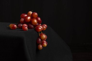 Bir masanın üzerindeki kırmızı üzümleri yakın plan ve siyah arkaplan, kopya alanı ile yatay olarak.