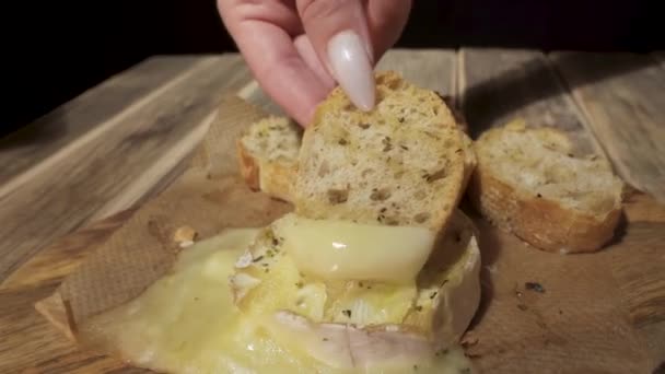 長い爪を持つ女の子は焼きにバゲットの一片を浸し溶融Camembertチーズ — ストック動画