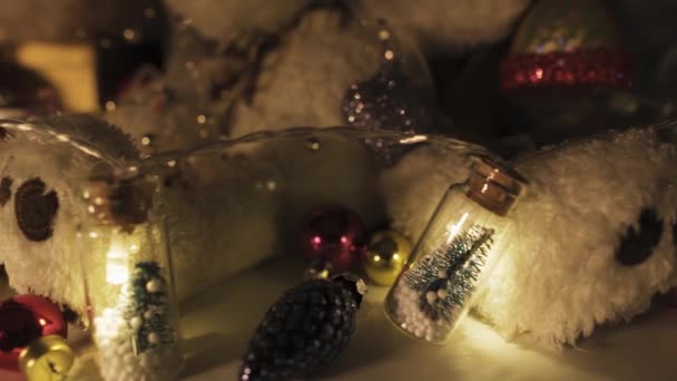 暗闇の中でクリスマスの装飾 贈り物や装飾 クリスマスツリーと瓶の中のガーランド キャンドルライト スライドショット — ストック動画