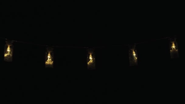 圣诞树花环 一个灯泡在一个小罐子里 有圣诞树和雪 黑色背景 — 图库视频影像