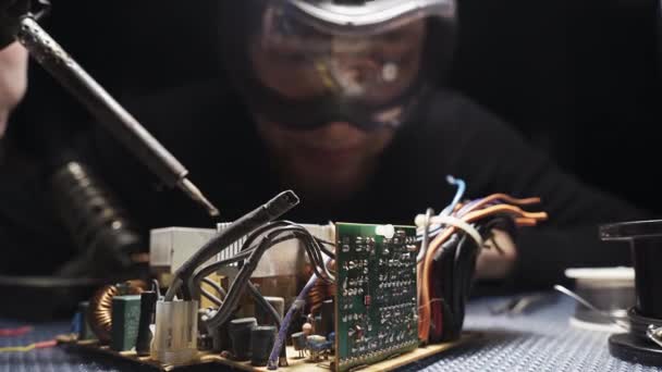 기술자는 기구를 수리하고 고글로 납땜을 슬라이드 클로즈업 — 비디오