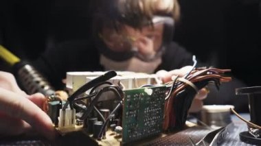 Usta elektrikli bir alet tamir ediyor, gözlüklü lehimler. Kaydırma atışı