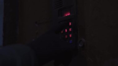 Kız ön kapıyı bir kombinasyon kilidiyle açıyor, karanlık bir girişte, yakın plan..