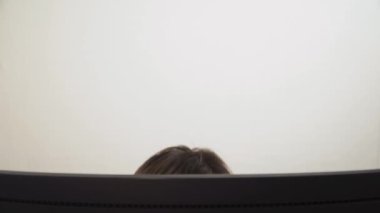 Bilgisayar monitöründeki genç bir adam su içiyor ve farklı duygular gösteriyor. yakın plan.