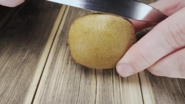 我用一把刀把猕猴桃切成两半 放在一张木制桌子上 — 图库视频影像