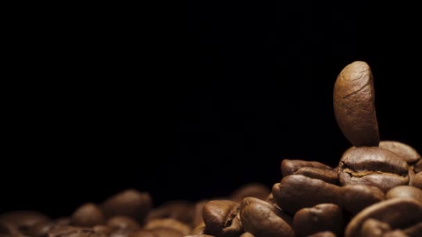 黒い背景にコーヒー豆が一つ コーヒー豆の山の上に回転します 接近中 — ストック動画