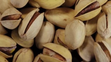 Tuzlu fıstıklı kabuk. Dönüşümlü hareket ediyor. Fıstık serpintisi. Yakın plan. Yukarıdan görüntüle.