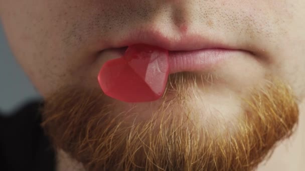 Jovem Com Casaco Preto Barba Vermelha Comendo Goma Forma Coração — Vídeo de Stock