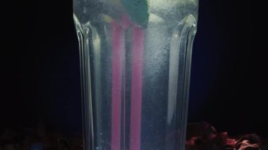 Siyah arka planda pembe pipetli bir mojito bardağı. Limonlu ve naneli. Kaydırıcı