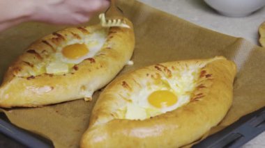Kız geleneksel Khachapuri yumurtasıyla hazırlıyor. Hamur ve peynir, fırına koyun.
