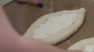 Kız geleneksel Khachapuri yumurtasıyla hazırlıyor. Hamur ve peynir, fırına koyun.