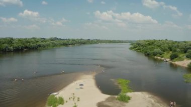 Drone. Nehrin üzerinden uç, kır evleri. Tekneler nehir boyunca yelken açar. İnsanlar yüzüyor. Ada