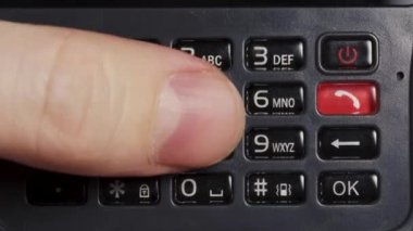 Erkek eli cep telefonunun eski siyah tuşlarına basar, yakın plan..