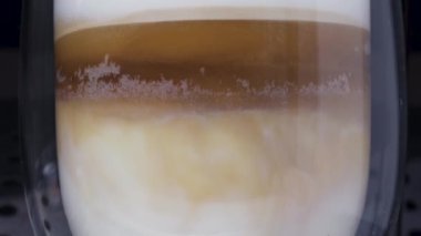 Kahve makinesi bir cappuccino yapar. Çift şeffaf bir camda yakın plan, yukarı doğru hareket
