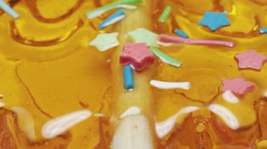Şeker serpiştirilmiş turuncu lolipop, yakın çekim, hareketli üst görünüm
