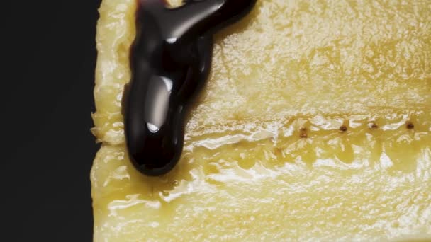 バナナを半分に切りチョコレートを垂らし右にスライド黒の背景をクローズアップし — ストック動画