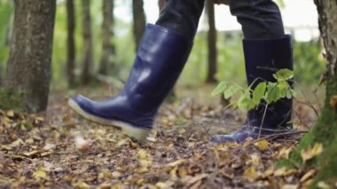Güneşli bir ormanda, botlu bir kız mantara basıyor, yakın plan..
