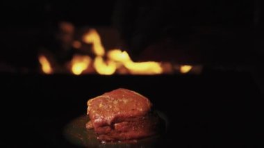 A piece of beef for a fillet mignon against the background of fire, revolves. I wrap it with marbled beef bacon.