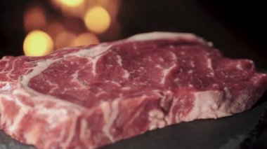 The steak is close-up, spinning on a rock against a background of fire.