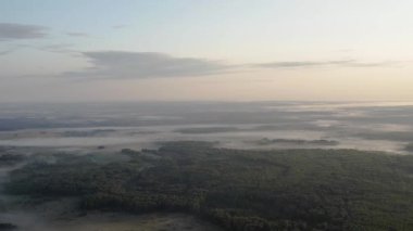 Drone video. Summer. Dawn with fog over the forest and lake.