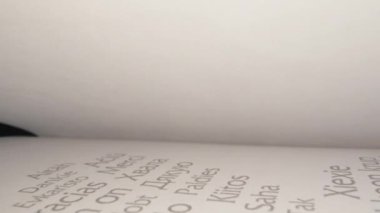 Macro view inside book slide dolly shot with laowa probe lens. Camera moves between paper book pages. Extreme close-up text printed Thank you in different languages