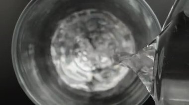 I pour clean water from a glass bottle, the camera is inside the glass, top view. Slider Dolly extreme close-up inside. Laowa Probe
