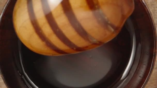 蜂蜜の木製のプレート 木製のスプーンは蜂蜜 スーパーマクロに浸されます スローモーション スライダードリーのクローズアップ ラオワプローブ — ストック動画