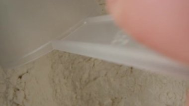 I take out a measuring spoon from a jar of flour, top view. Dolly slider extreme close-up inside. Laowa Probe