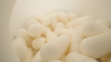 White jar with pills, capsulamia. Dolly slider extreme close-up inside. Laowa Probe
