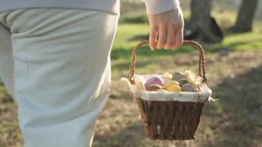 In the sunny Forest early in the morning, a girl walks with a basket of Easter Eggs. Rear view, close-up. Slow motion