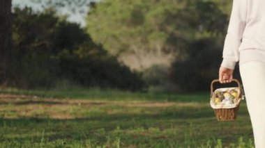 A girl in White Walks through the forest with a basket of Easter eggs. Sunny morning, slow motion